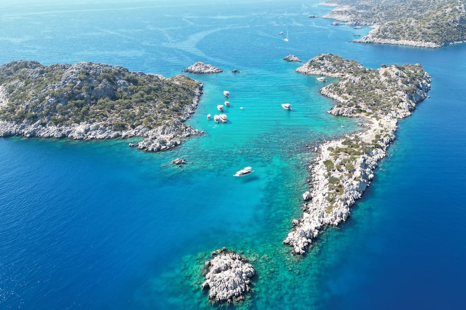 An aerial view of a coastal area with rocky islands and clear turquoise waters.
