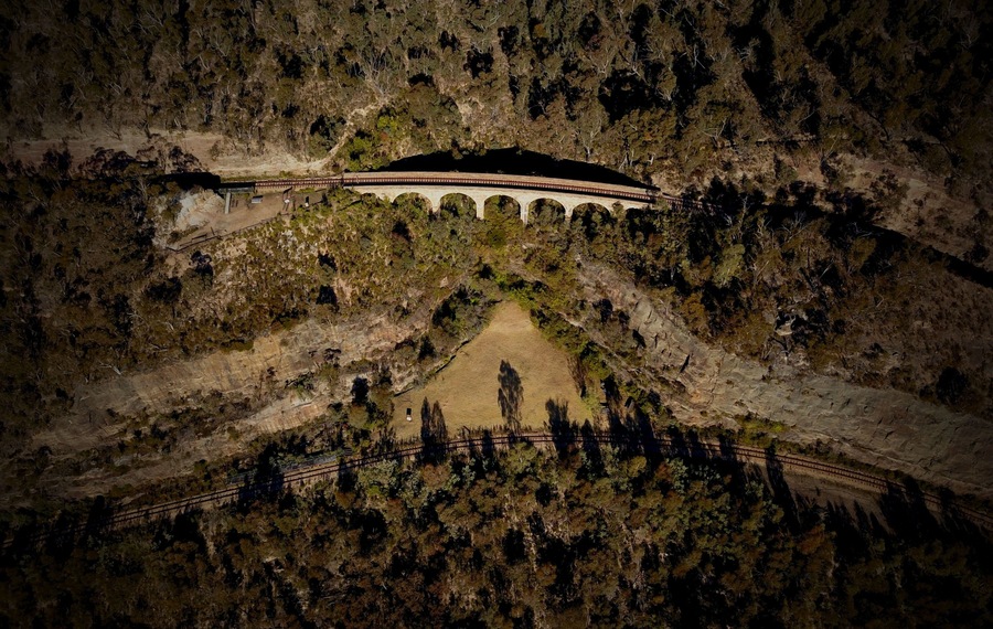 We spent yesterday arvo bush-bashing down to the Zig Zag Railway viaducts above Lithgow, NSW and looking around the place for a few hours.
In this shot you can see the No. 1 Viaduct on the Top Road track. A little further down is the larger No. 2 Viaduct. And on the Bottom Road (which is the train line near the bottom of this pic) is the No. 3 Viaduct.
Comprising rock cuttings, classical sandstone viaducts and tunnels, the Lithgow Zig Zag was, and remains to this day, a magnificent piece of engineering. Construction of this part of the rail system began in 1866 and was completed by the late 1890s. The line was decommissioned in 1910 with the construction of the Ten Tunnels deviation which is still in use today by state rail.
Back in the early 1970s, volunteers worked to bring the line back into operation as an iconic tourist railway which ran for decades, bringing with it tourism dollars to the wider Lithgow area.
In 2013, a huge bushfire swept through the area and destroyed a lot of the infrastructure and equipment used by the Zig Zag Railway. Since that day work has proceeded to slowly bring the tourist train line back into operation It is hoped it'll be up and running again in the next year or so.
Follow @zigzagrailway on Insta and Facebook for updates.
For more pics of this awesome area, check out the 4WD Swagman facebook page.
#zigzagrailway
#lithgow
#stoneviaduct
#railway
#bluemountains
#djimavicpro