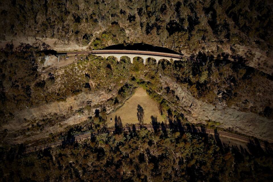 En stenviadukt som sträcker sig över en dal, med en grusväg som leder fram till den.