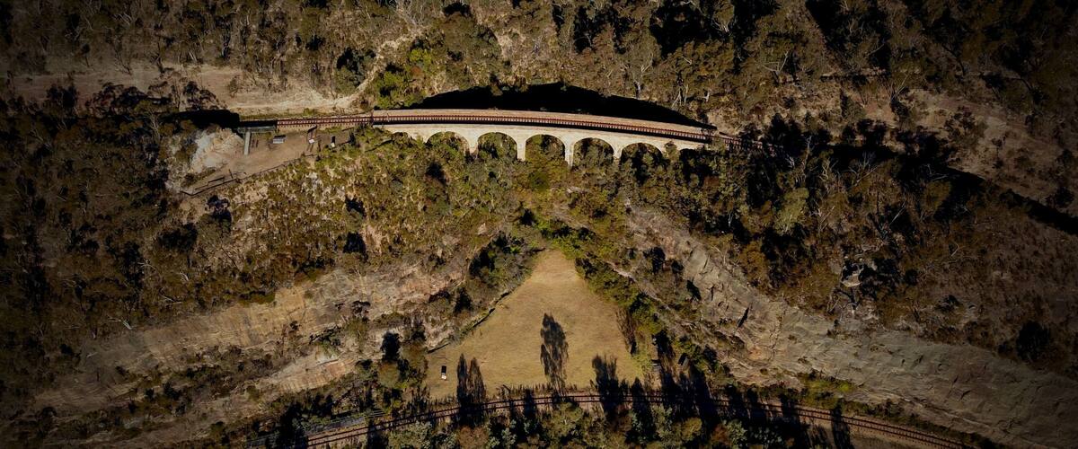 A stone viaduct over a valley with a dirt path leading to it.
