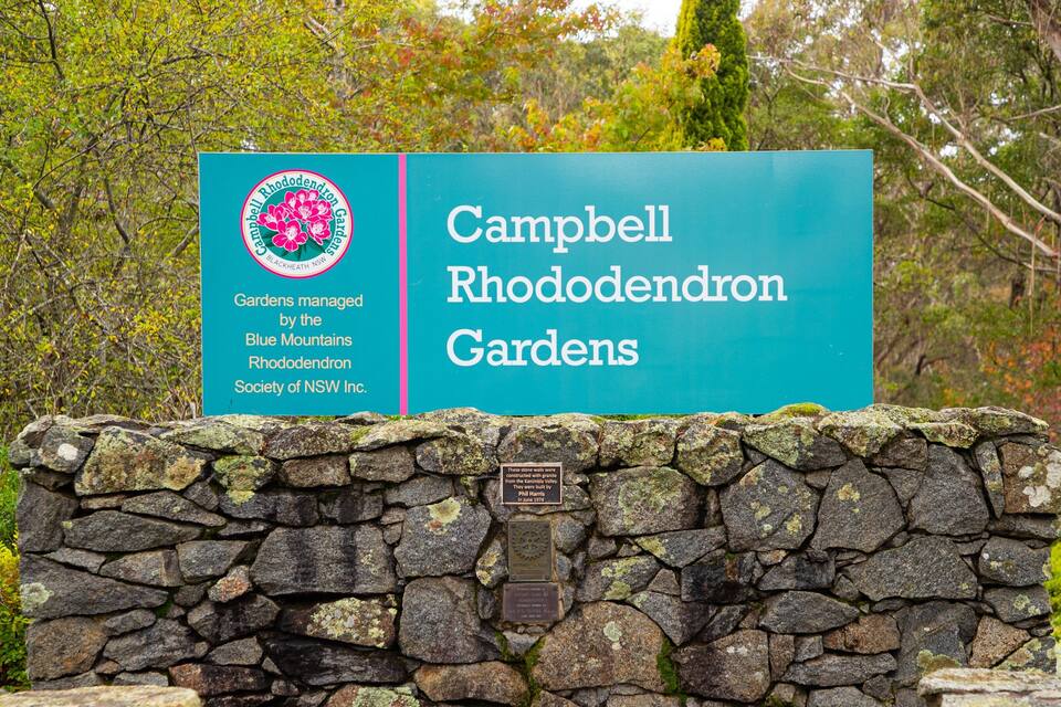 Schild für den Campbell Rhododendron Garten, mit einer Steinmauer im Vordergrund.