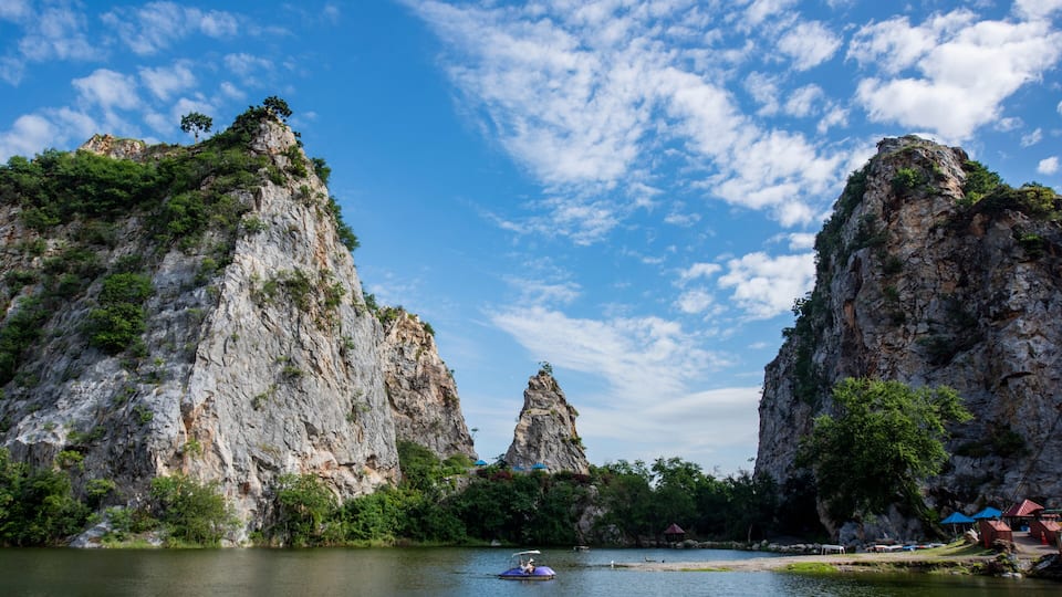 A river with a boat, surrounded by rocky cliffs and greenery.