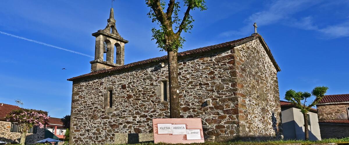 A stone church with a bell tower and a sign reading "IGLESIA ABIERTA".