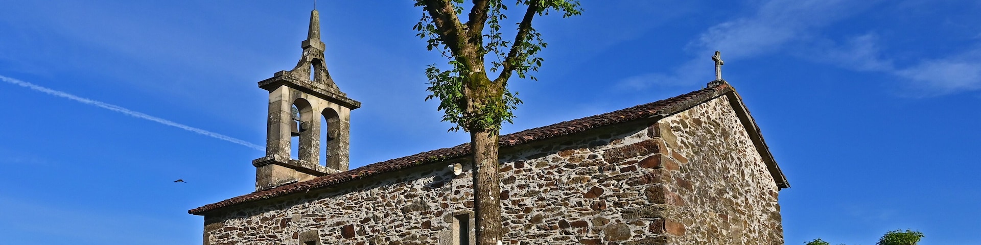 A stone church with a bell tower and a sign reading "IGLESIA ABIERTA".