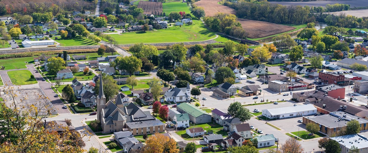 A town with a church, residential houses, and a green field.