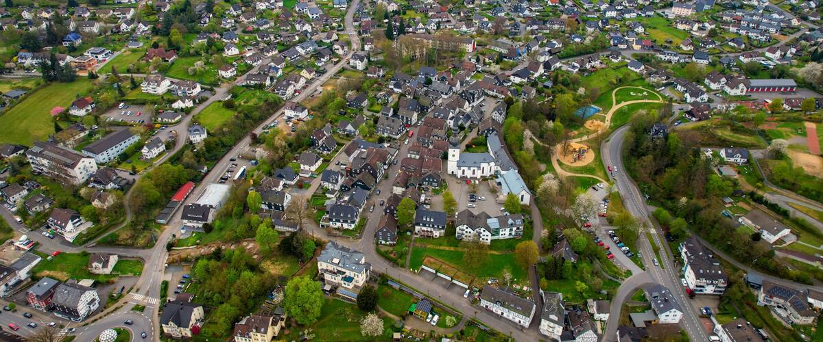 An aerial view of a densely populated residential area with numerous houses, roads, and green spaces.