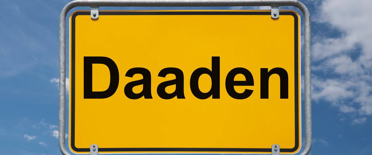 A yellow sign with the word "Daaden" against a blue sky with clouds.
