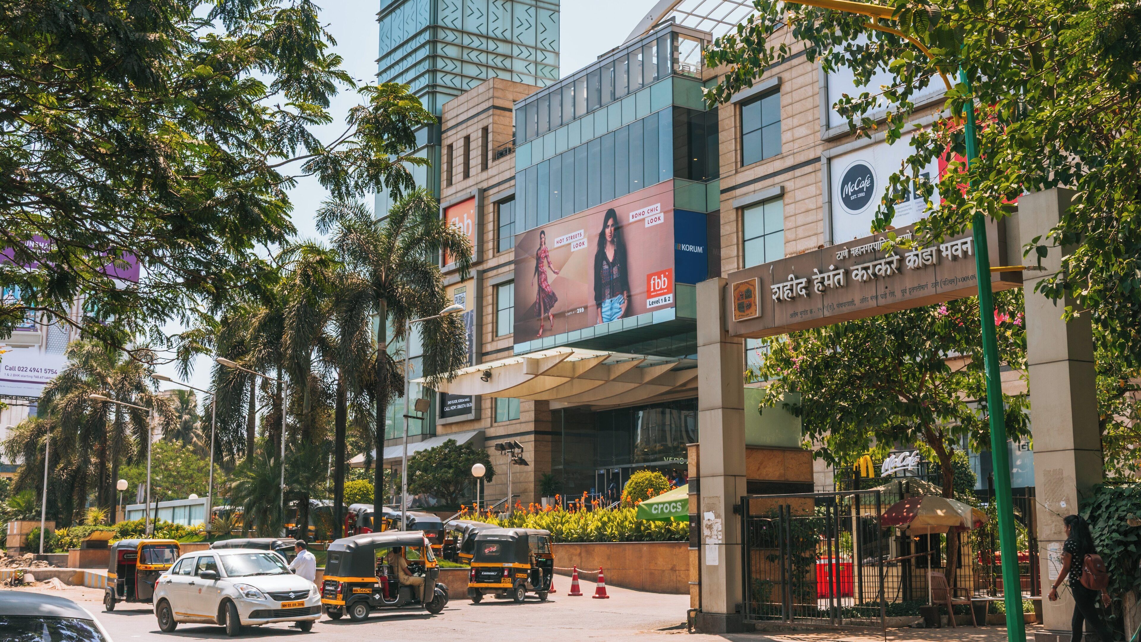 Korum Mall in Thane West bustling with shoppers and auto rickshaws during a sunny day in Maharashtra, India