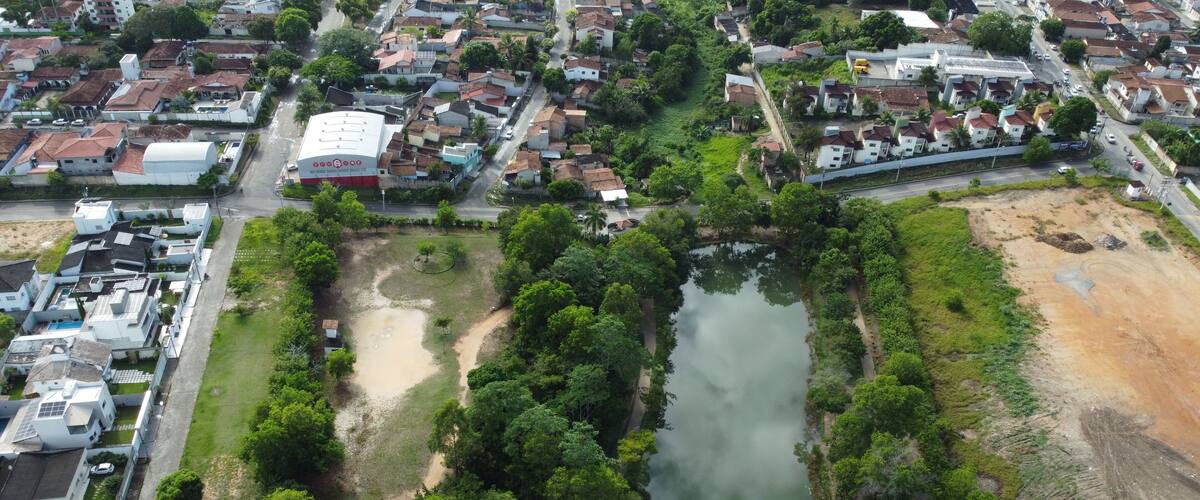 An aerial view of a residential area with a river, green spaces, and a large white building with a red roof.