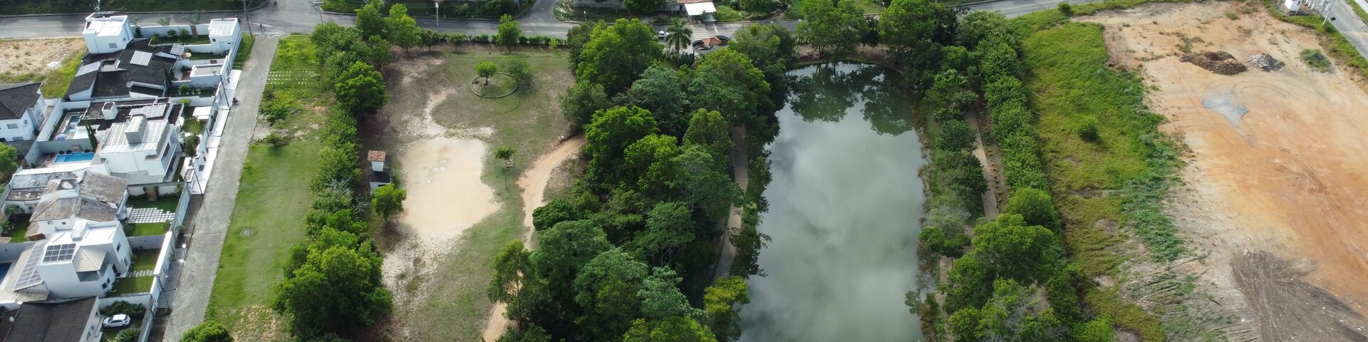 An aerial view of a residential area with a river, green spaces, and a large white building with a red roof.