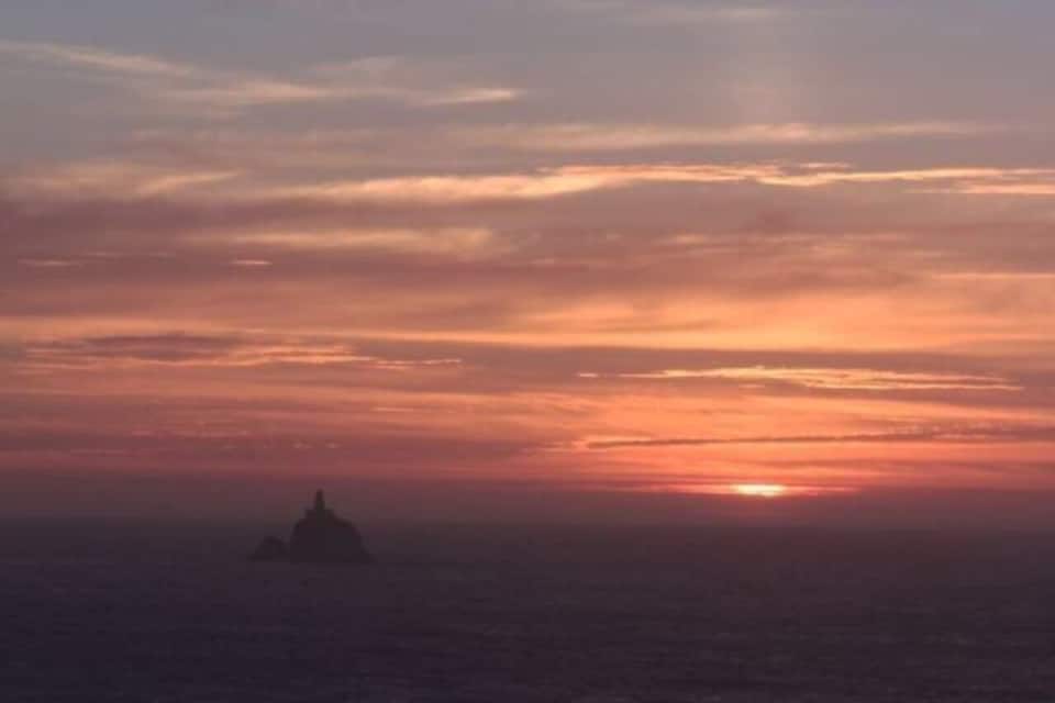 A sunset over the ocean with a silhouette of a small island.