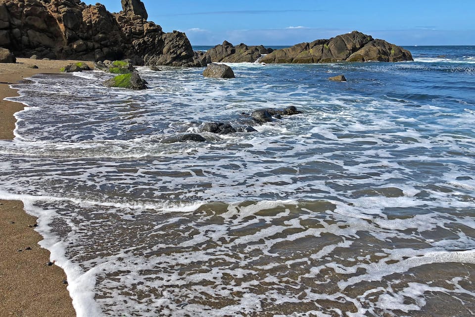 Una costa rocosa con olas rompiendo sobre la orilla.