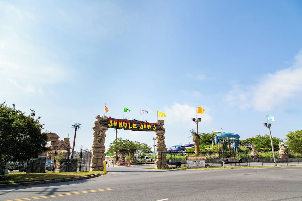 An entrance archway with 'Jungle Jim's' written on it, surrounded by flags and a blue structure in the background.
