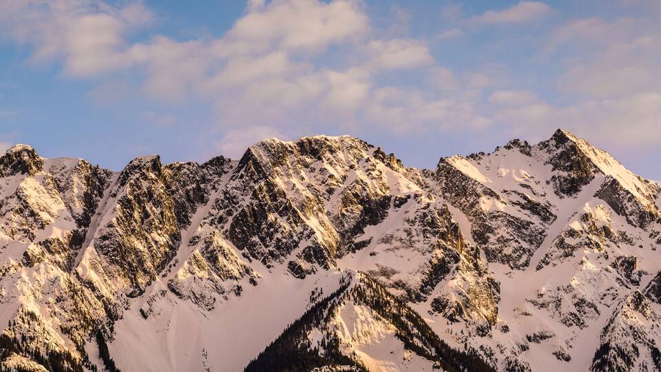 A snow-covered mountain range with sharp peaks and a clear sky.