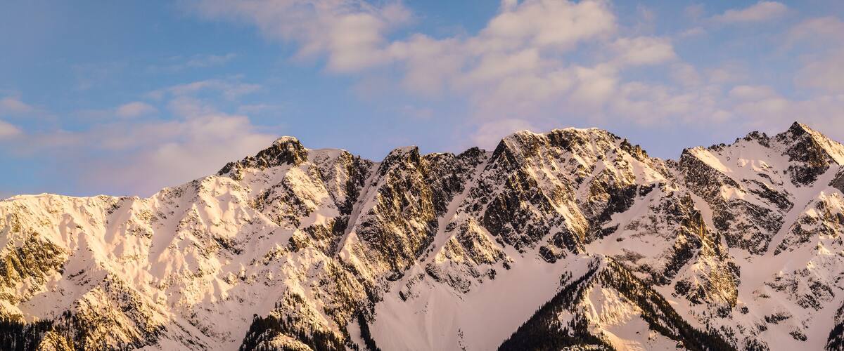 A snow-covered mountain range with sharp peaks and a clear sky.