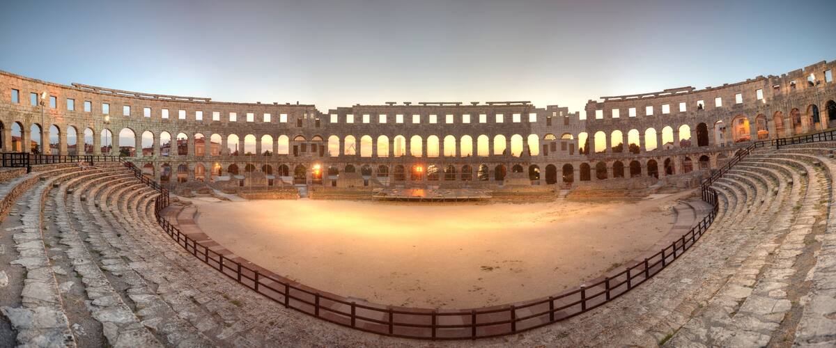 An ancient amphitheater with stone seating and a central stage.