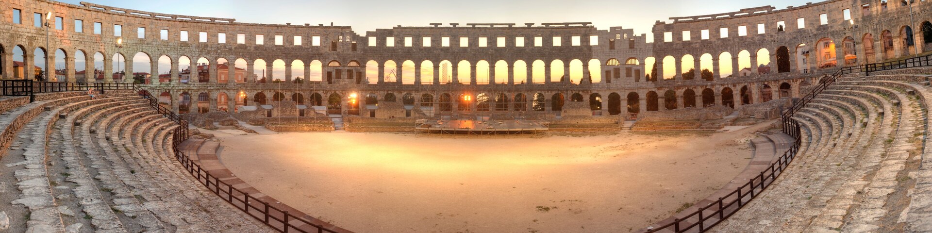 An ancient amphitheater with stone seating and a central stage.