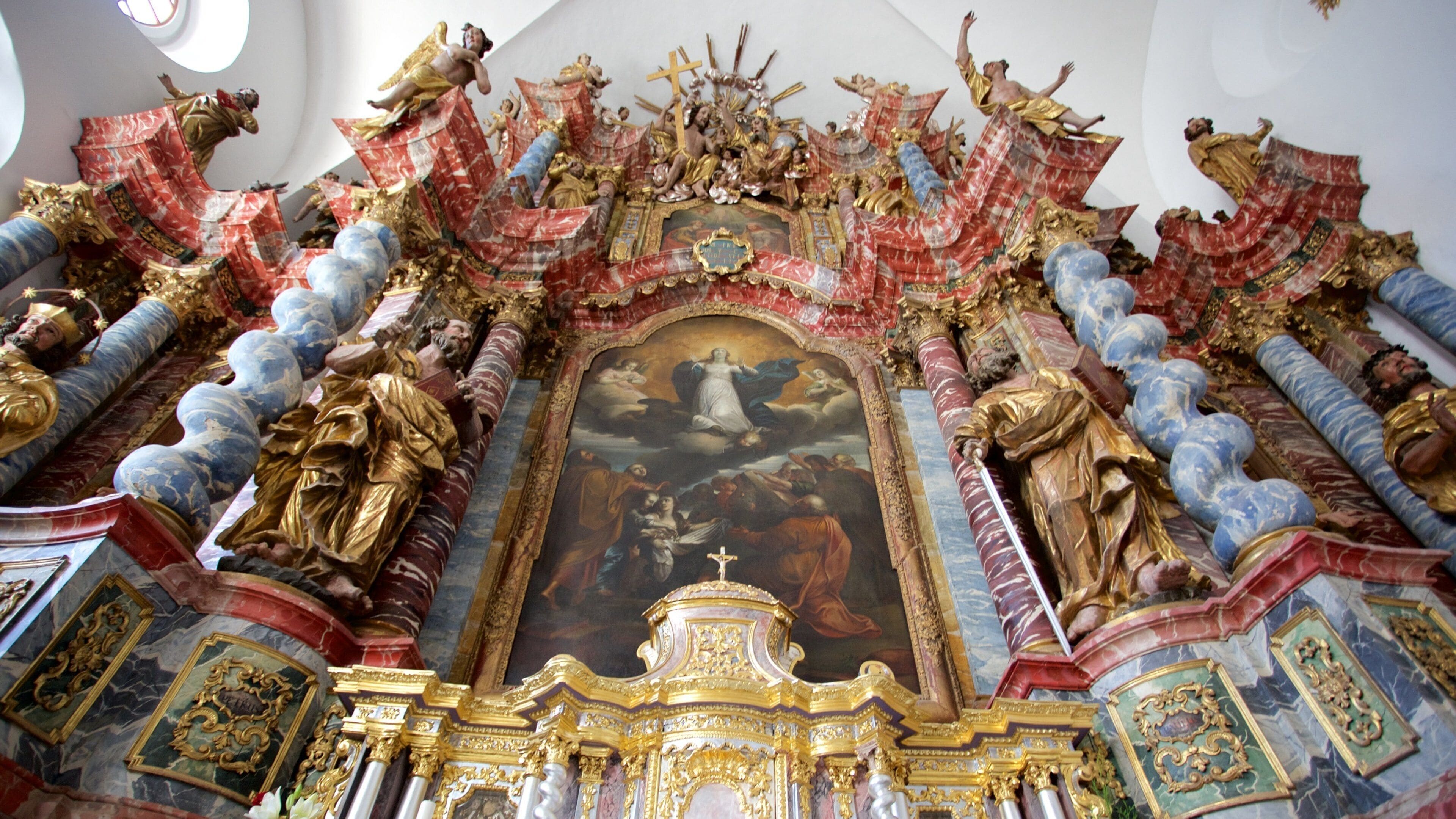 A richly decorated altar with religious statues and a central painting.
