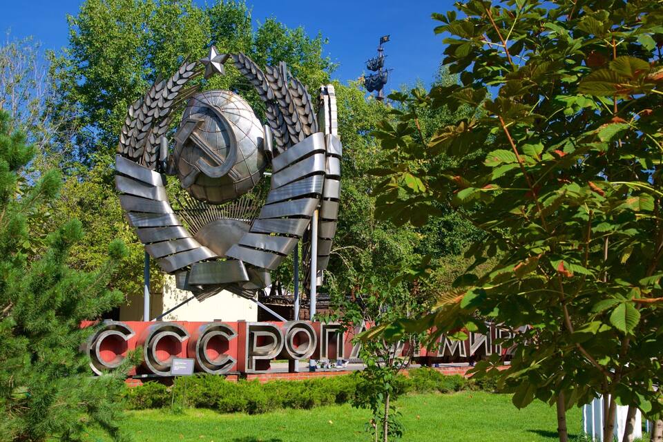 A large metallic sculpture with circular and leaf-like elements, surrounded by greenery and a building with 'CCCP' text.