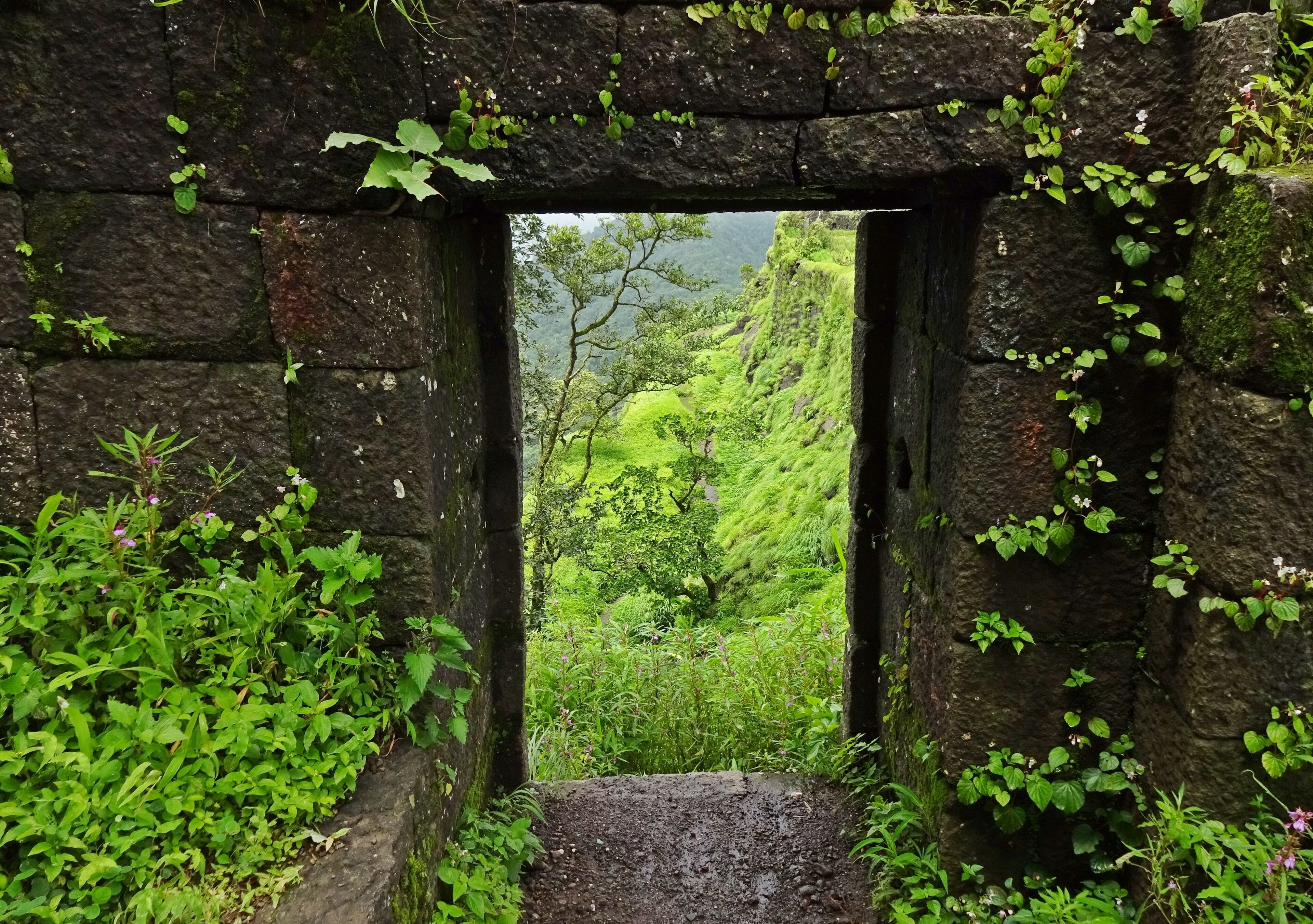 A stone archway leading to a lush green valley.