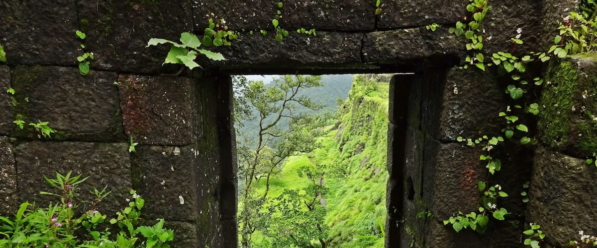 A stone archway leading to a lush green valley.
