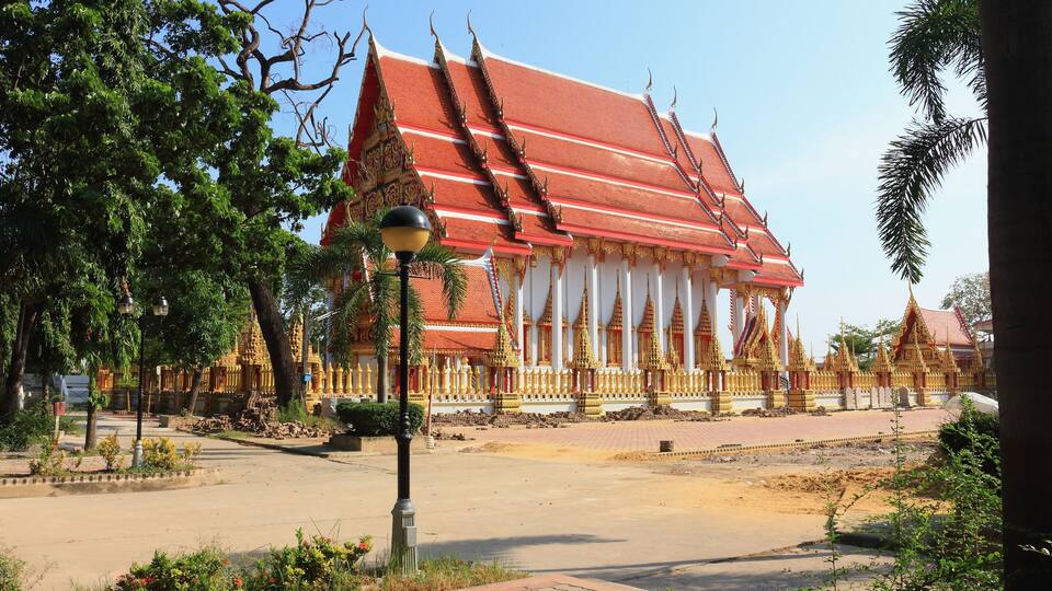 A traditional Thai temple with a red roof and golden decorations.