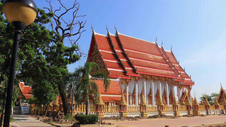 A traditional Thai temple with a red roof and golden decorations.