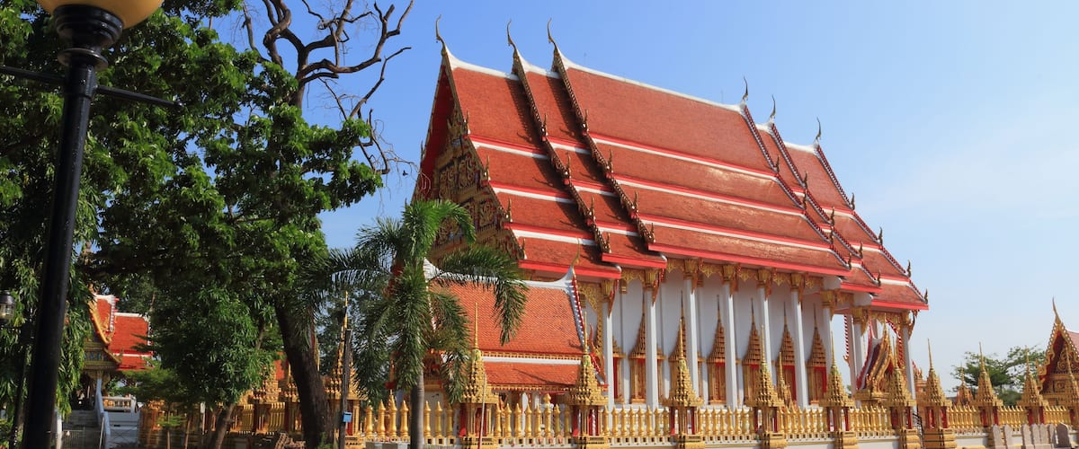A traditional Thai temple with a red roof and golden decorations.