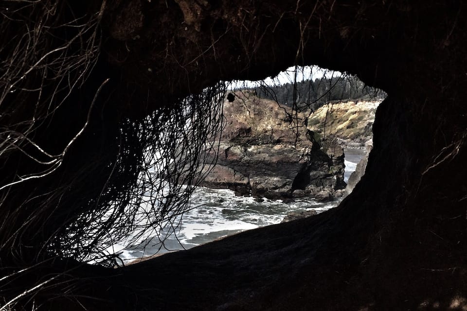 Entrada de uma caverna com vista para um rio e paisagem rochosa.