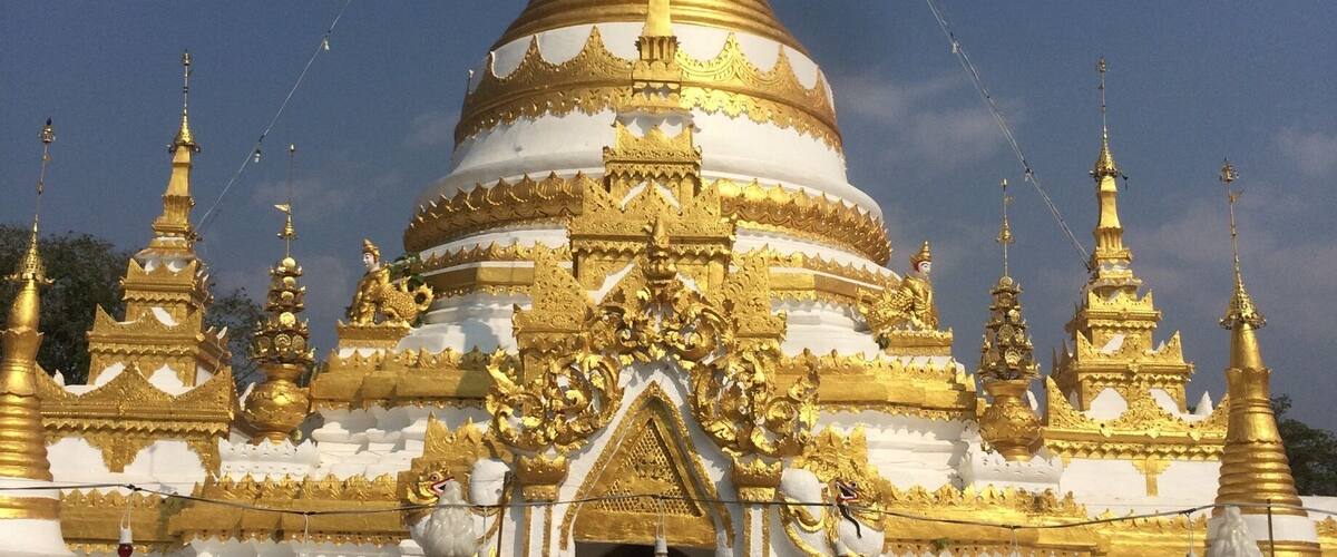 A golden pagoda with intricate designs and a white base.