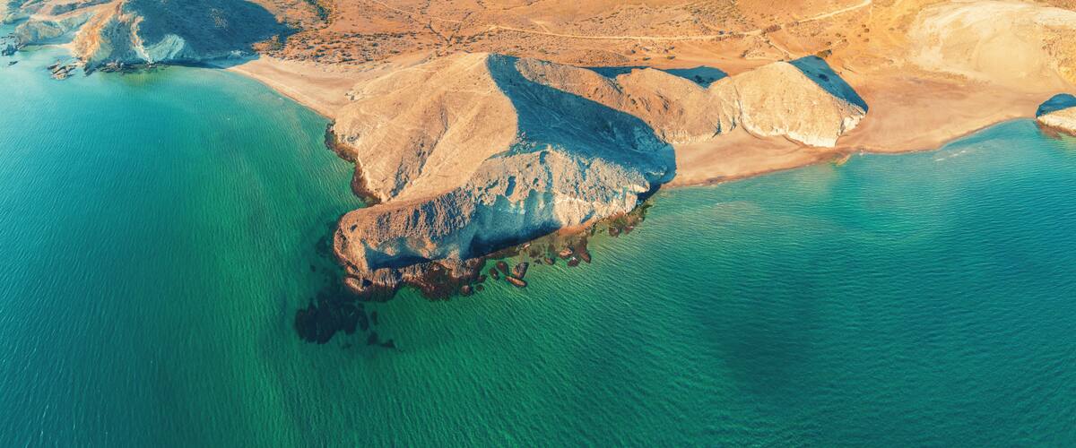 A coastal landscape with a prominent rocky outcrop surrounded by turquoise waters.