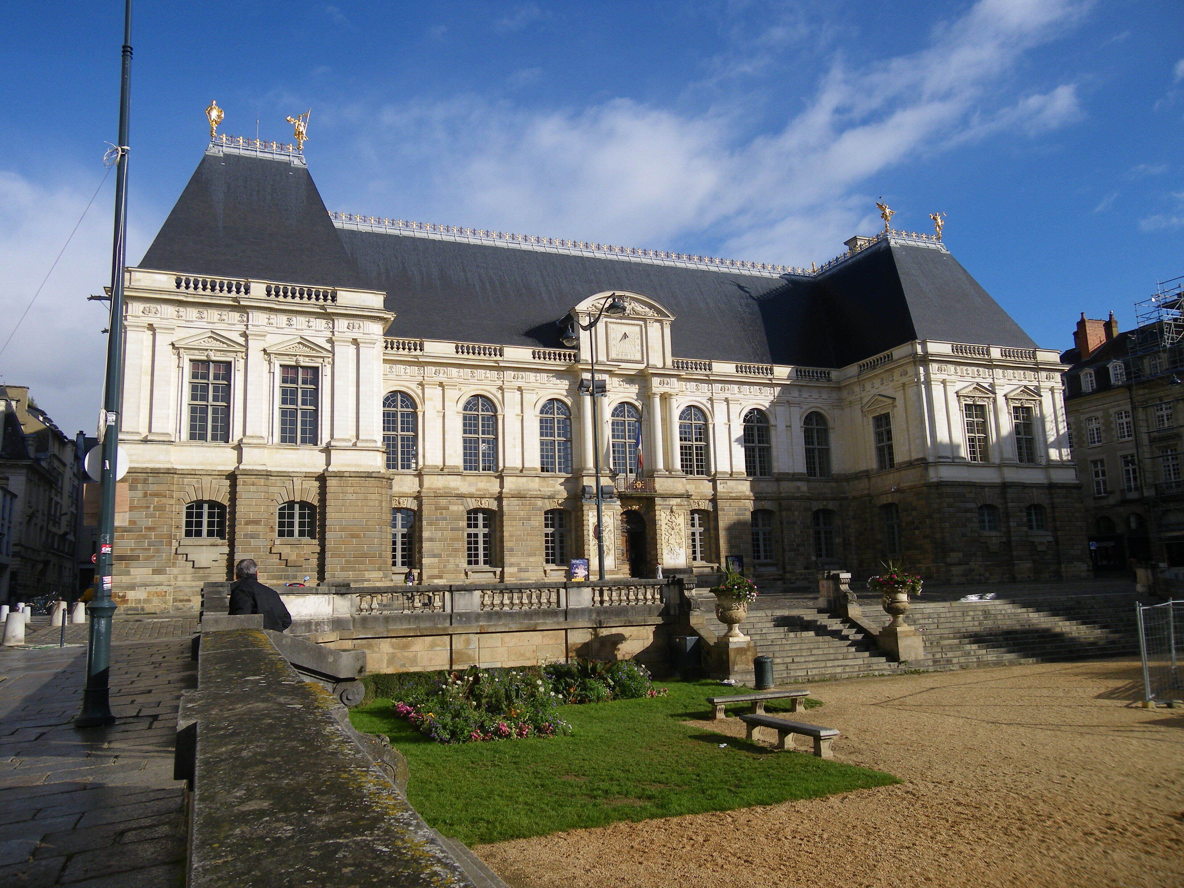 A historic building with a large courtyard, a fountain, and a statue.