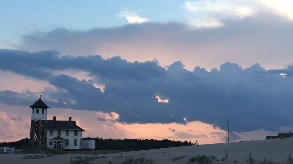 A coastal landscape with a white house and a lighthouse.