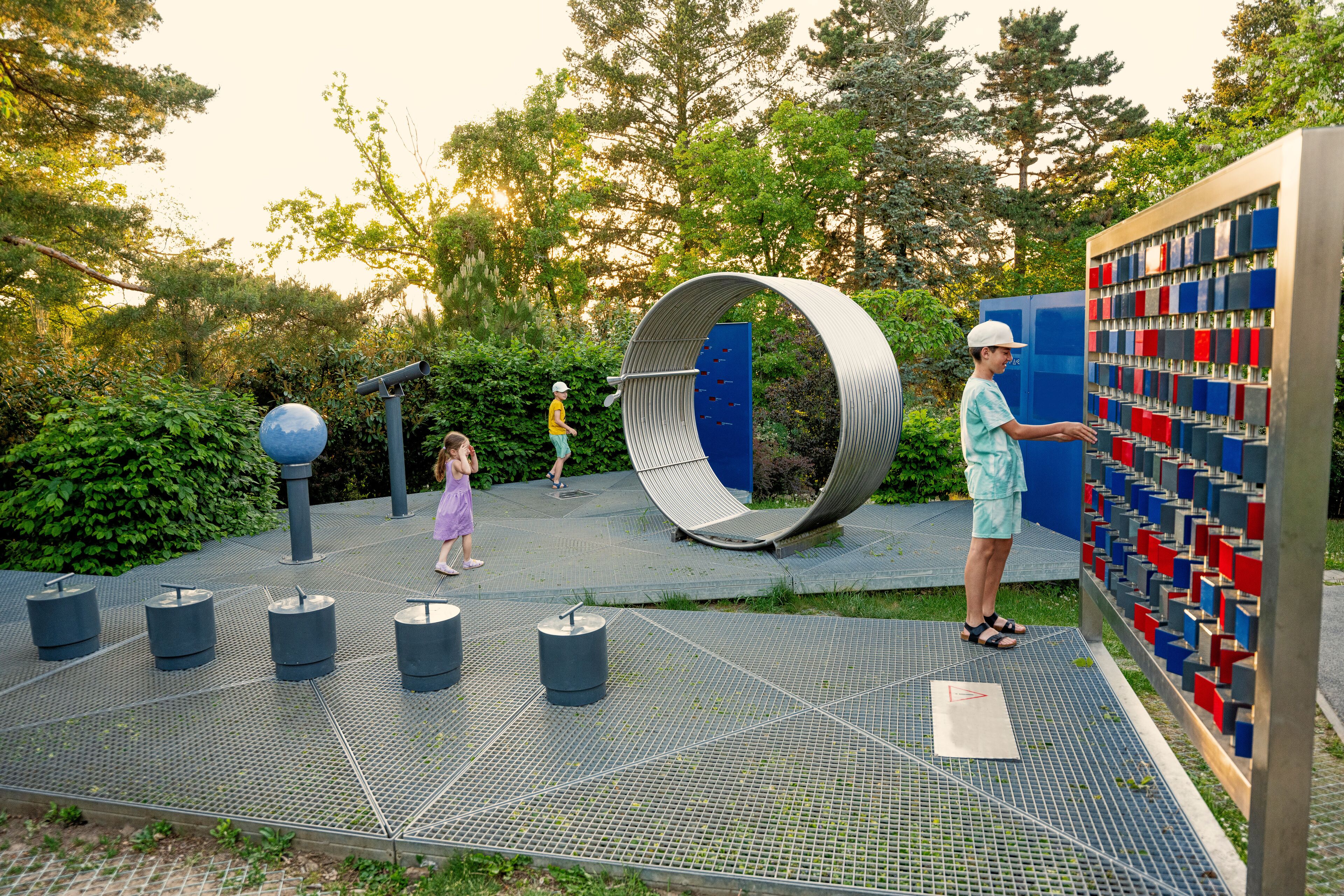Kids play with telescopes and other stuff at observatory park in planetarium.
