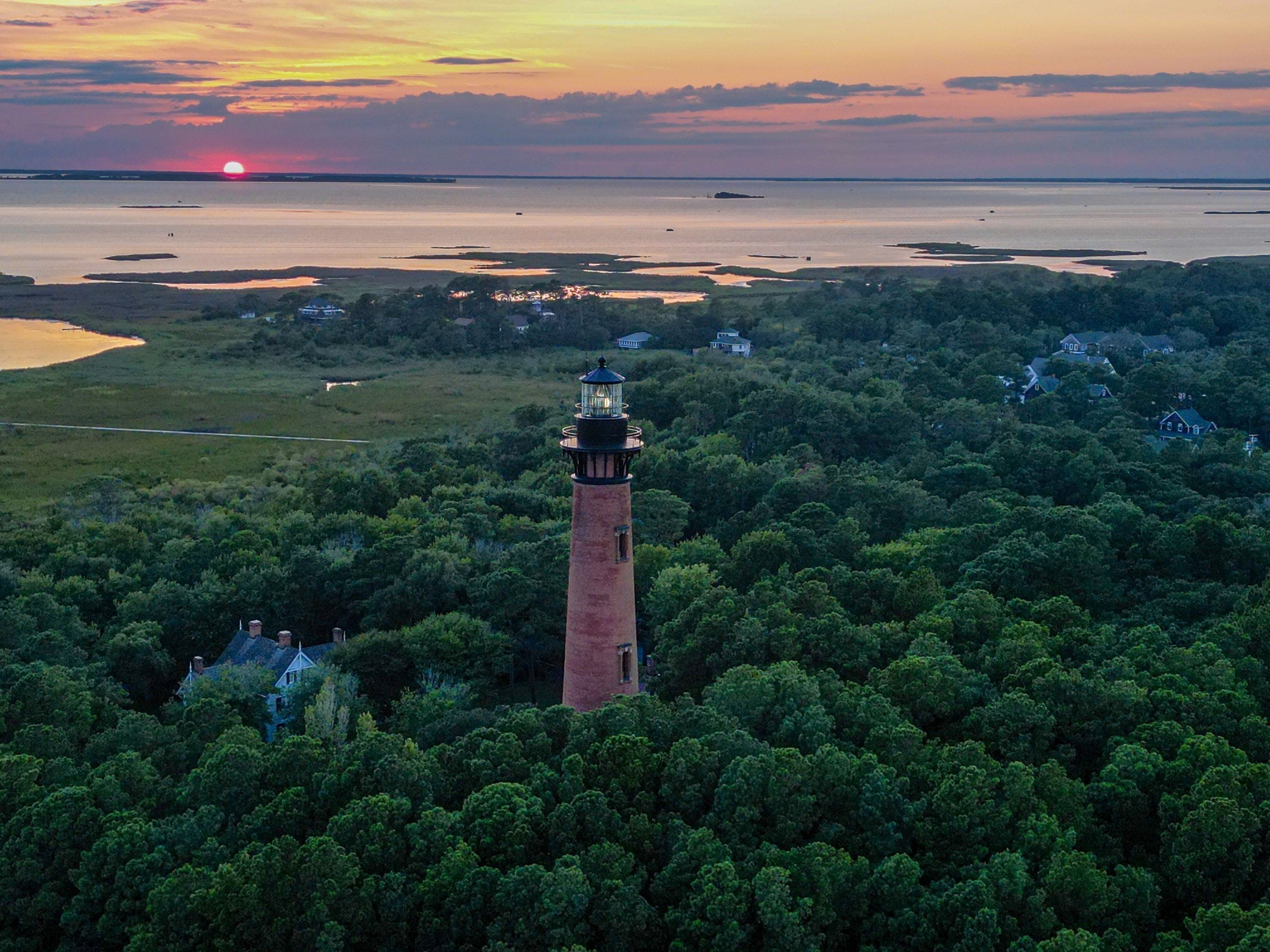 Aerial view of Currituck Beach Lighthouse on an island surrounded by lush green trees