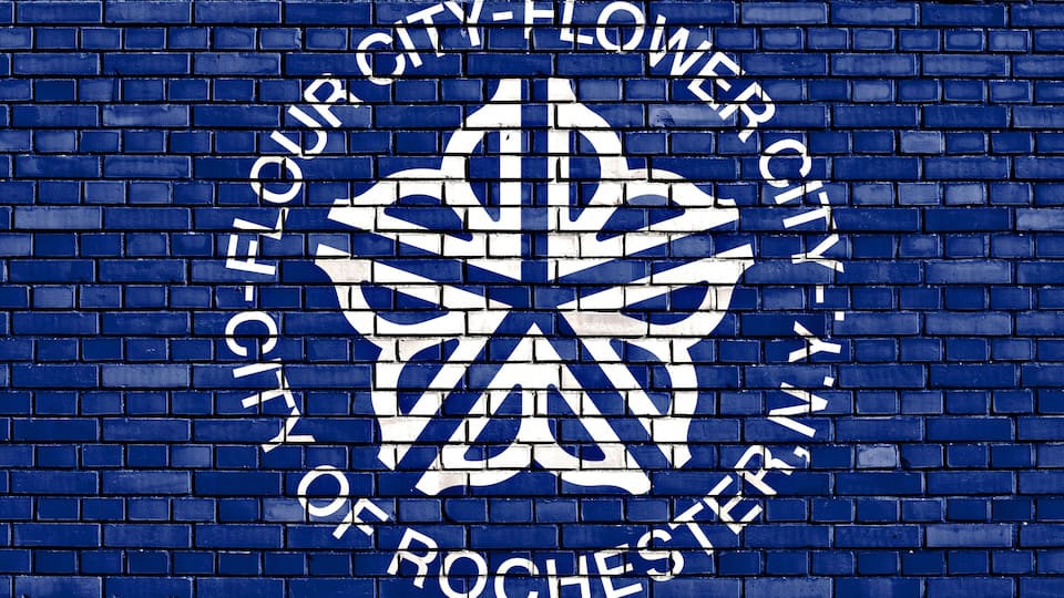 A blue brick wall with a white logo and text reading "CITY OF ROCHESTER".