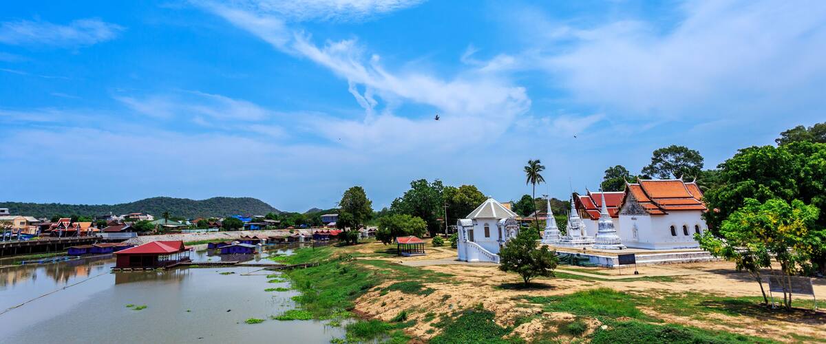 A riverside view with traditional buildings, a temple, and a clear blue sky.