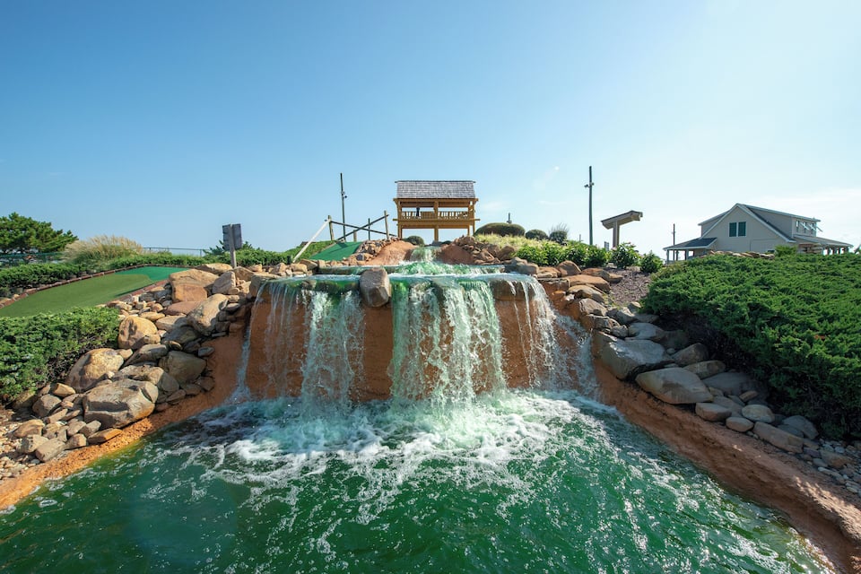 A waterfall cascading into a pool, surrounded by rocks and greenery.