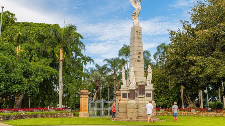 Queens Park showing a garden and a statue or sculpture as well as a small group of people