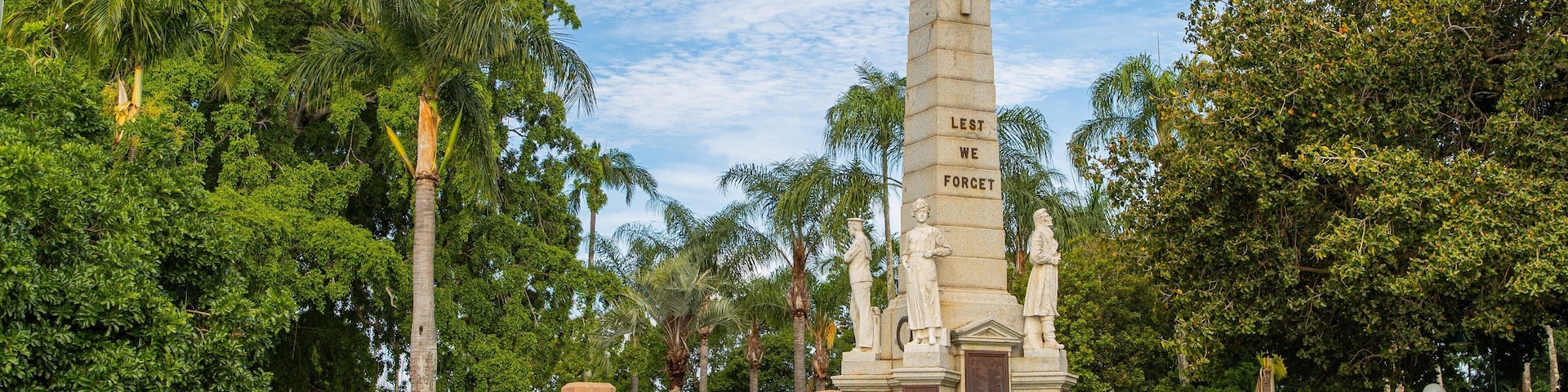 Queens Park showing a garden and a statue or sculpture as well as a small group of people
