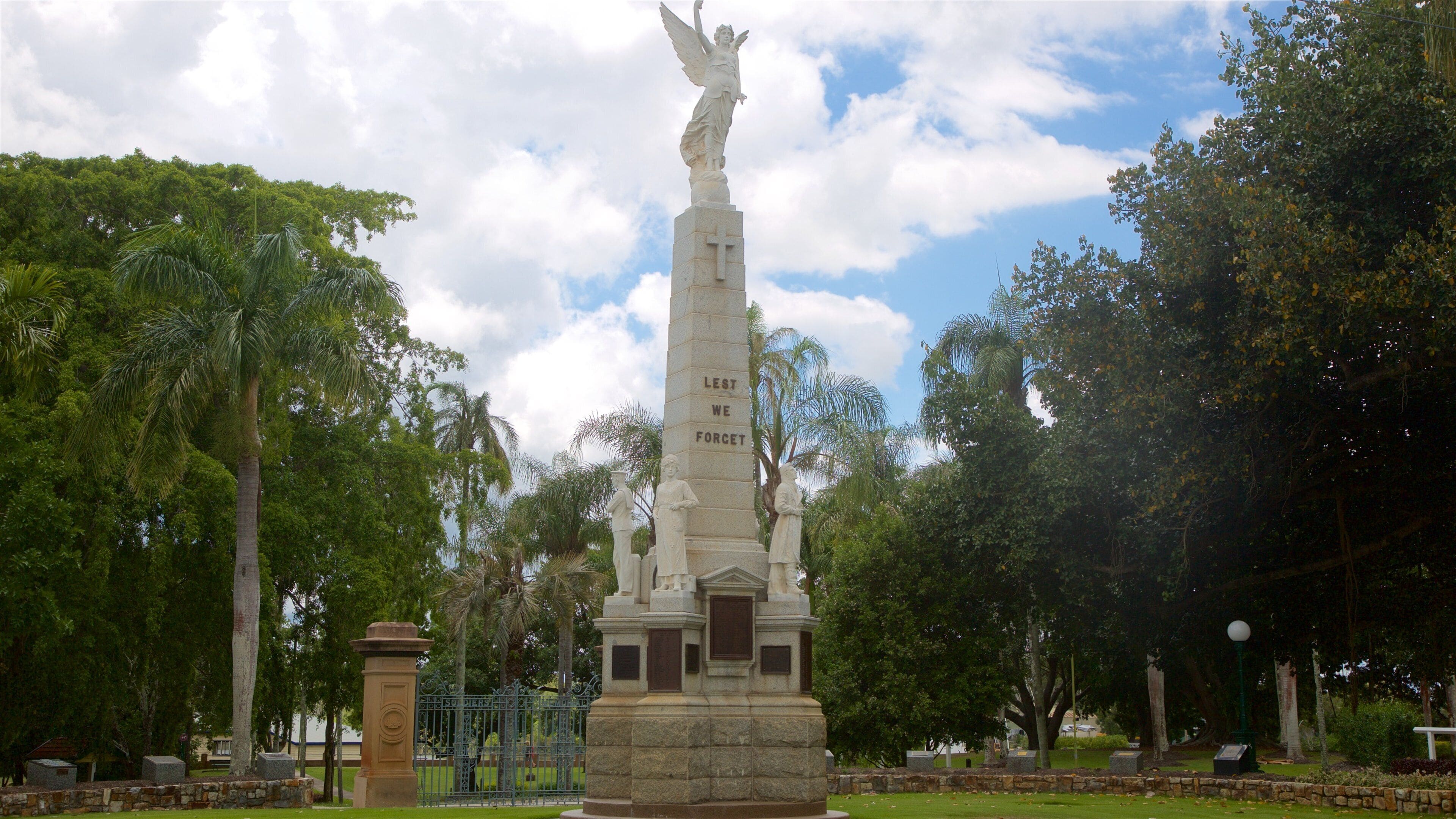 Ein Denkmal mit einem Kreuz und der Inschrift „Lest We Forget“, umgeben von Bäumen.
