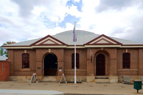 A brick building with a red roof, arched windows, and a flagpole.