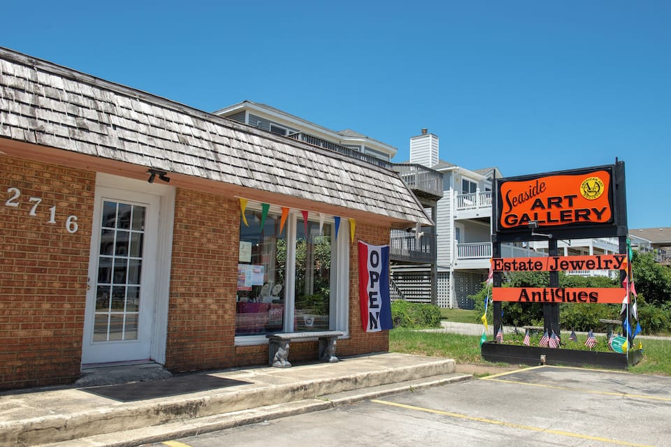 A brick building with a sign for Seaside Art Gallery, Estate Jewelry, and Antiques.