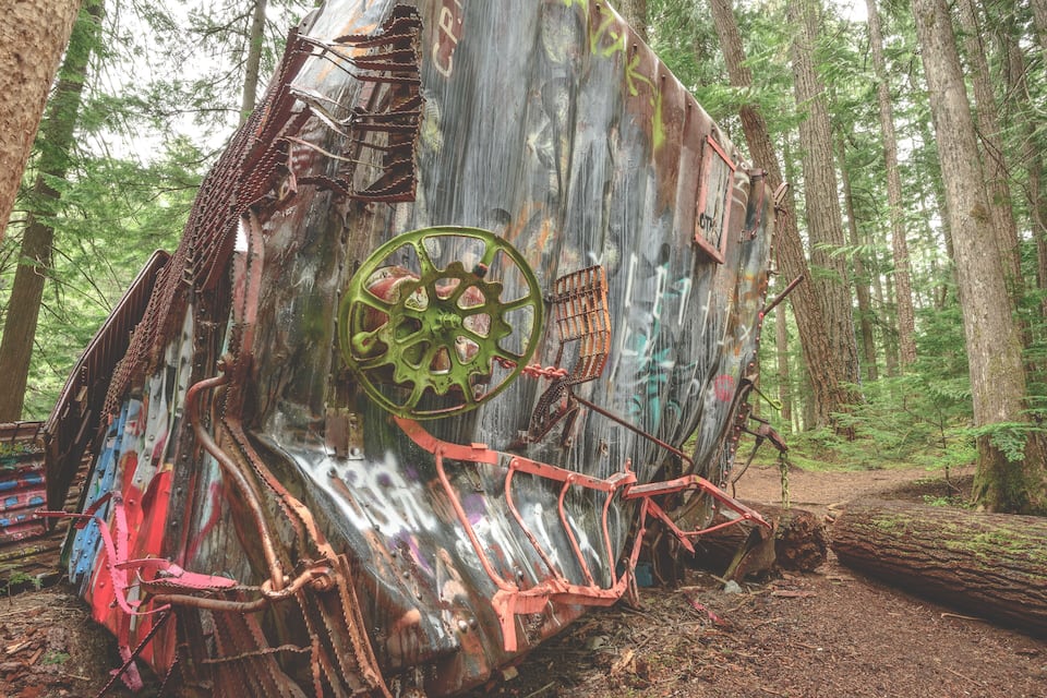 A rusted, graffiti-covered metal structure in a forest.