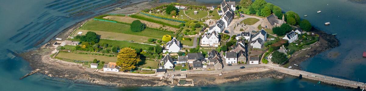 An aerial view of a coastal village with houses, a church, and a large shipwreck.