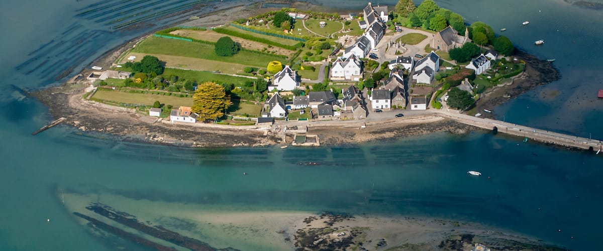 An aerial view of a coastal village with houses, a church, and a large shipwreck.