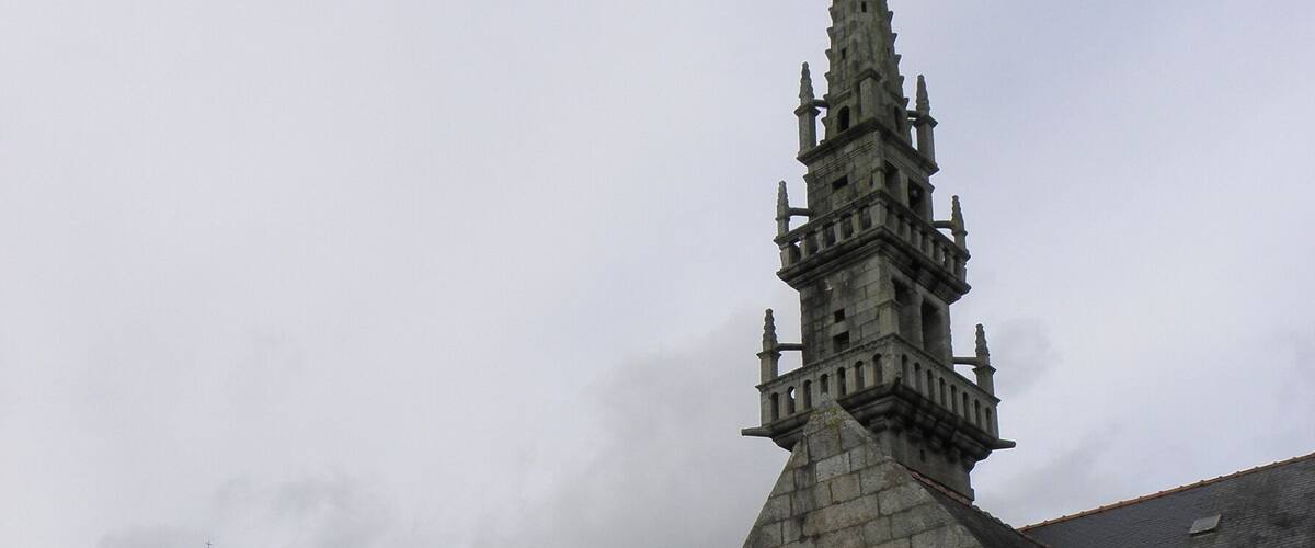 A historic stone church with a tall spire and a smaller adjacent building.