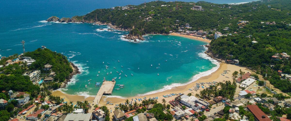 A coastal town with a beach, boats, and a lighthouse.