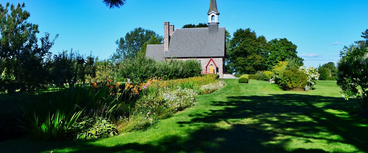 A church surrounded by lush greenery and a clear blue sky.