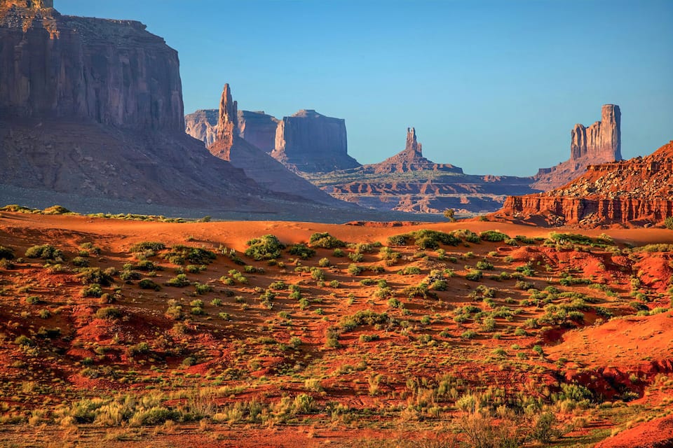 A desert landscape with prominent rock formations and sparse vegetation.